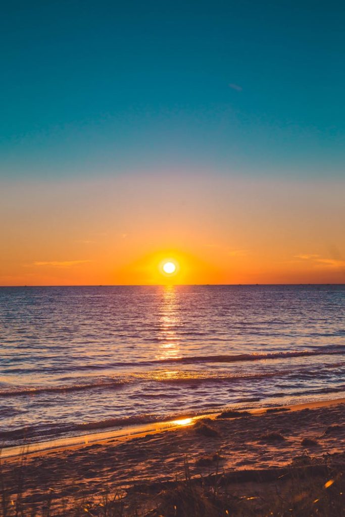 Beautiful sunset over a calm ocean with vibrant sky, perfect for relaxation themes.